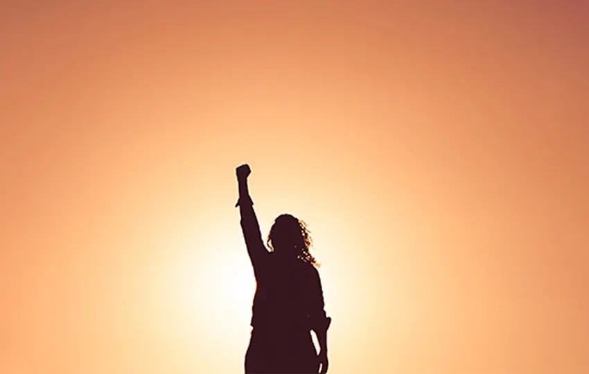 Woman raising her fist in empowerment at sunset
