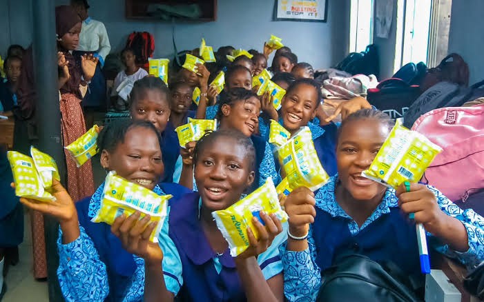 Girls smiling with sanitary pads at a Pad A Damsel outreach